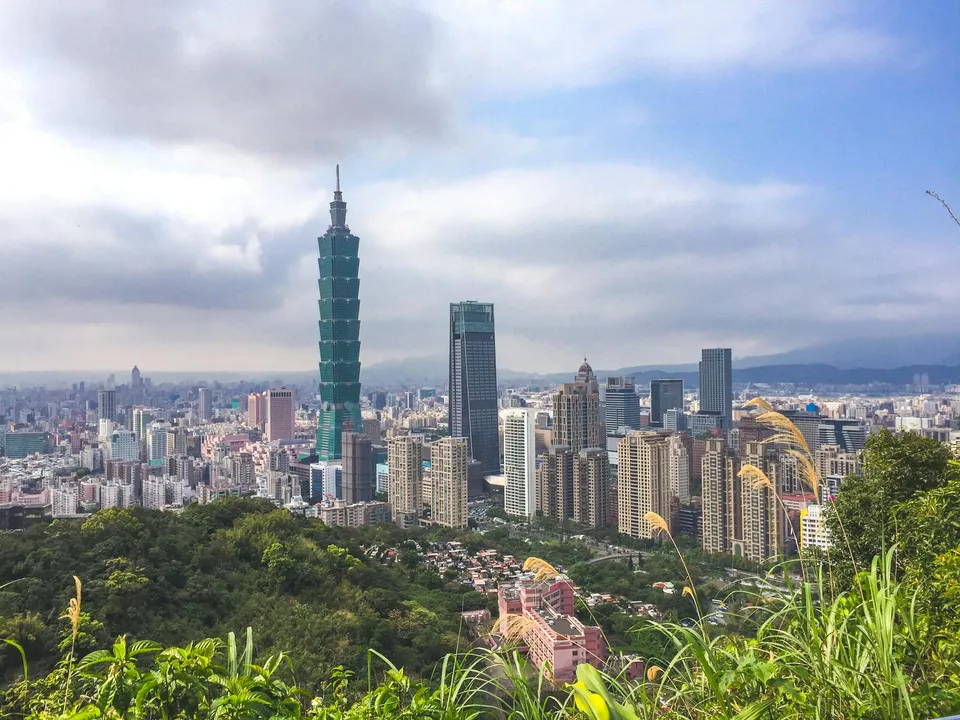 Aerial view of Taipei 101 and the Taiwan skyline framed by lush mountains